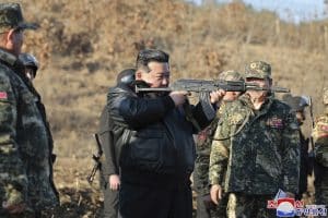 Îmbrăcat în geacă de piele, Kim Jong Un ține strâns o armă în umăr, în timpul unei inspecții la o importantă bază de antrenament